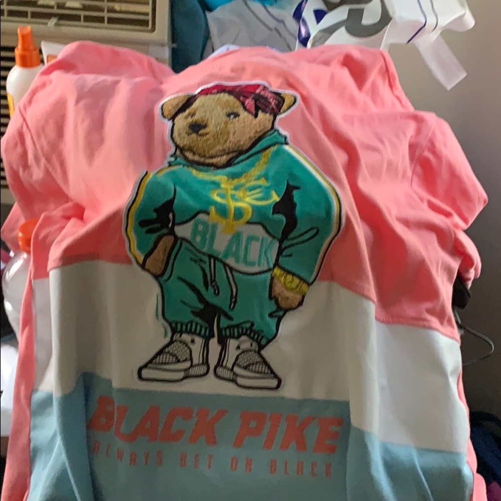 A pink white and blue t shirt with a bear on it.
